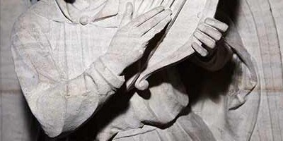Close up of stone carving of an angel playing a harp